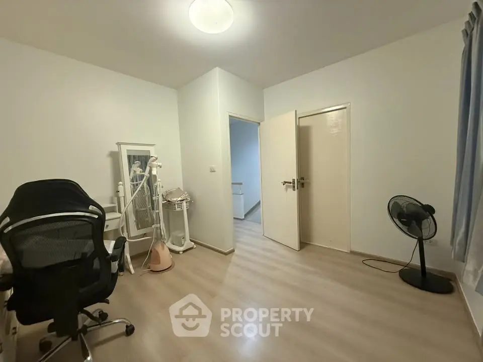 Spacious study room with modern chair and fan, ideal for productivity.