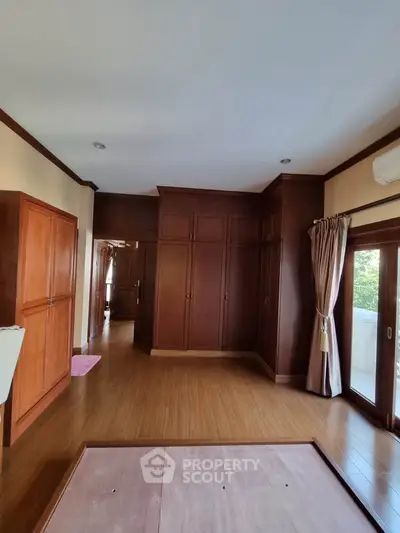 Spacious bedroom with wooden flooring and large built-in wardrobes