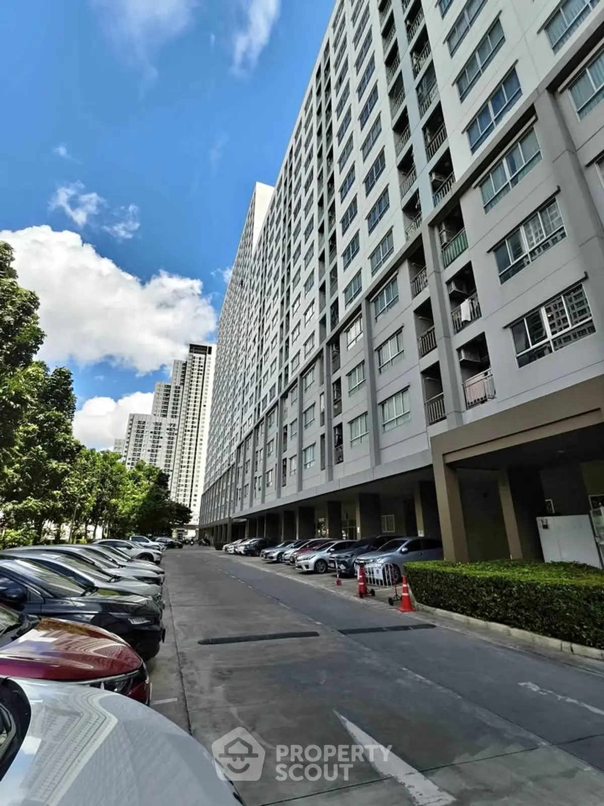 Modern high-rise apartment building with parking area and clear blue sky