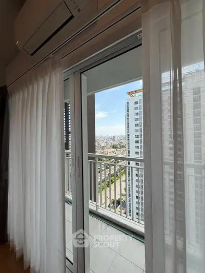 Spacious balcony with city view from modern apartment, featuring sliding glass doors and elegant curtains.