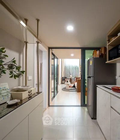 Modern kitchen with open layout leading to a cozy living room, featuring sleek appliances and stylish decor.