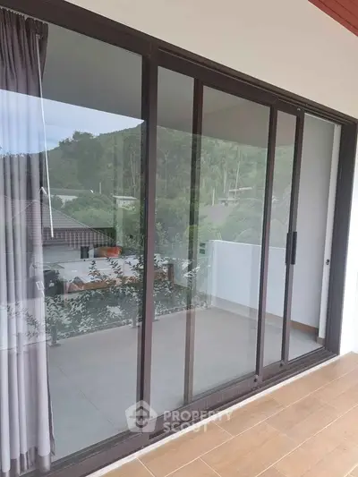Spacious balcony with sliding glass doors and scenic views of lush greenery.
