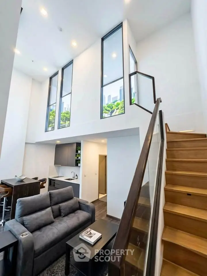 Stunning modern duplex with high ceilings and large windows, featuring a cozy living area and sleek kitchen.