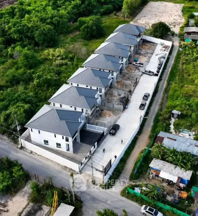 Aerial view of modern townhouse development surrounded by lush greenery, showcasing new construction and spacious layout.