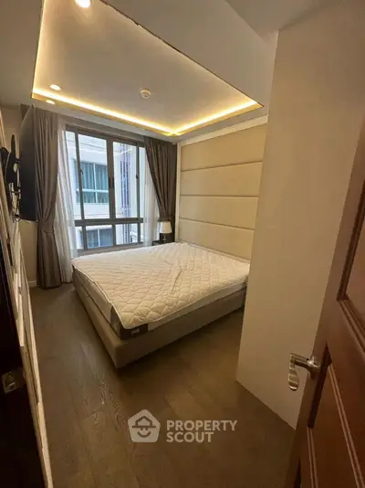 Modern bedroom with large window and stylish lighting in a contemporary apartment.