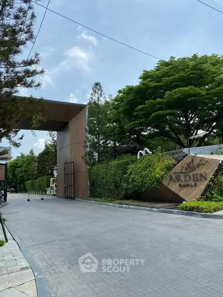 Luxurious gated entrance with lush greenery and modern architectural design.