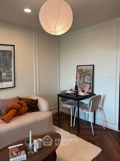 Cozy living room with stylish decor and dining nook, featuring modern furniture and warm lighting.