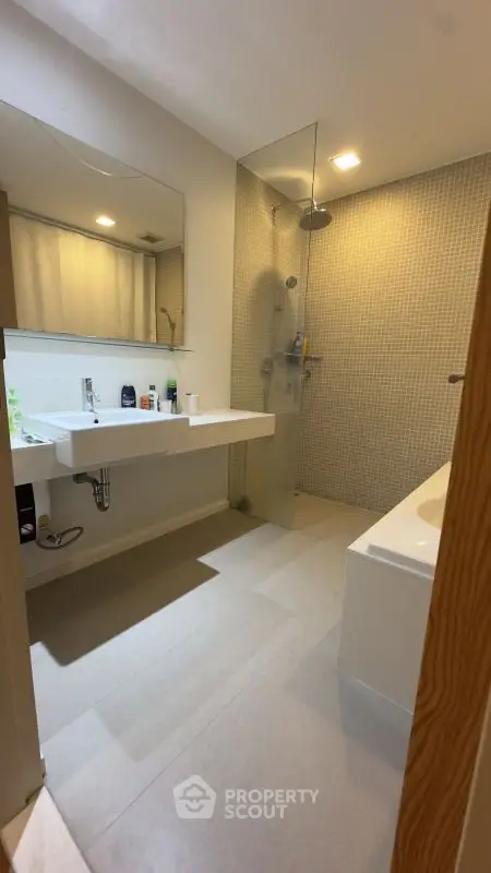 Modern bathroom with dual sinks, glass shower, and bathtub in stylish apartment.