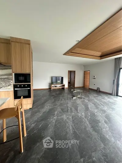 Spacious modern living room with sleek flooring and open kitchen layout, perfect for contemporary living.