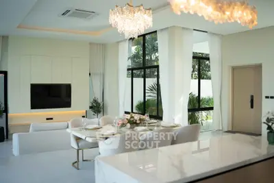 Luxurious open-plan living room with elegant dining area and large windows overlooking a lush garden.