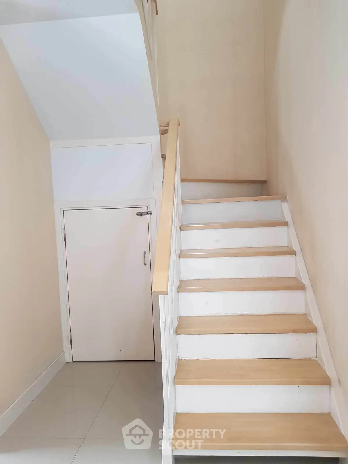 Modern staircase with wooden steps and white railing in a minimalist interior setting.