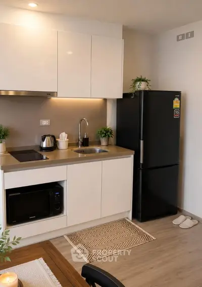 Modern kitchen with sleek cabinetry, black fridge, and built-in microwave in a cozy apartment.
