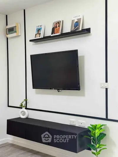 Modern living room with wall-mounted TV and sleek black furniture, perfect for stylish urban living.