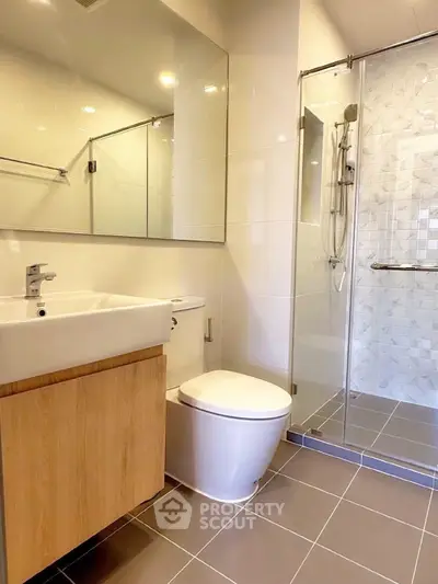 Modern bathroom with sleek fixtures and glass shower enclosure in contemporary apartment.
