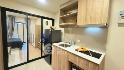 Modern kitchen with sleek cabinetry and open layout leading to cozy bedroom