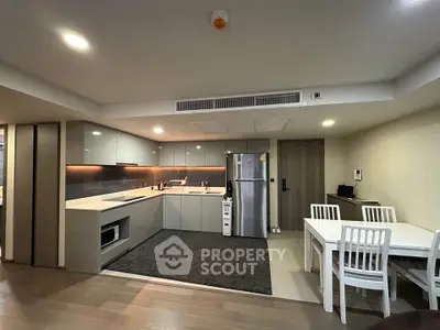 Modern kitchen with sleek design and dining area in open layout apartment.