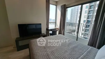 Modern bedroom with city view and balcony access in high-rise apartment