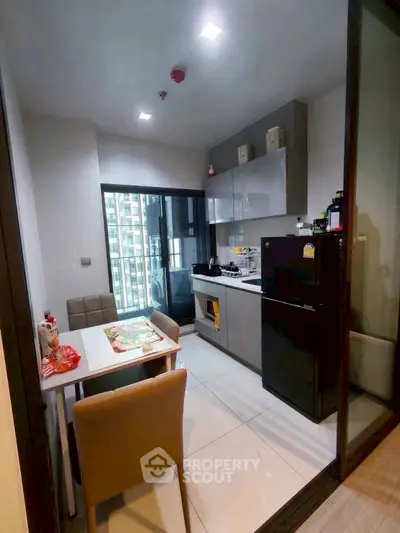Modern kitchen with sleek cabinetry and dining area in high-rise apartment