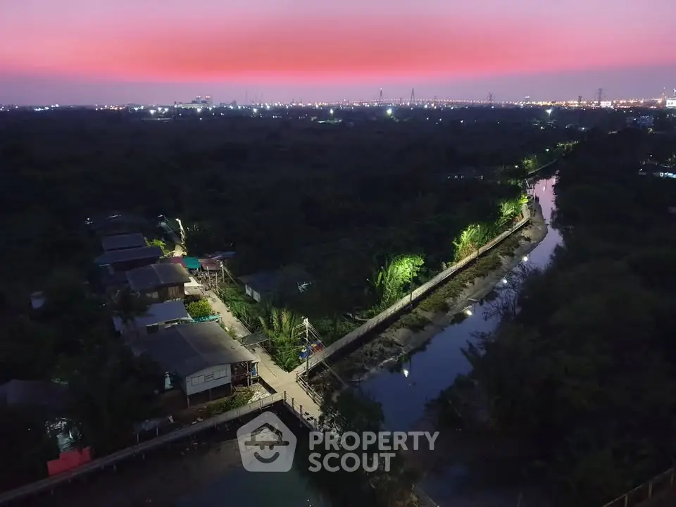 Stunning aerial view of serene riverside homes at dusk with vibrant sunset sky.