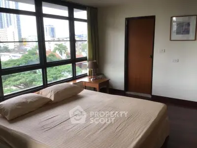 Spacious bedroom with large windows offering a stunning city view, perfect for urban living.