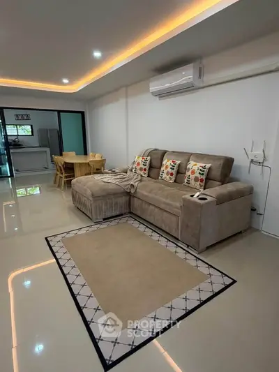 Spacious living room with modern sofa and dining area, featuring sleek flooring and ambient lighting.