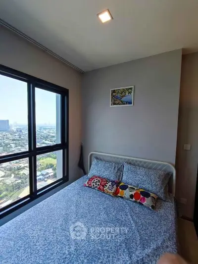 Cozy bedroom with stunning city view from large window, featuring colorful bedding and wall art.