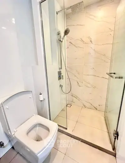 Modern bathroom with glass shower and sleek toilet in a contemporary apartment.