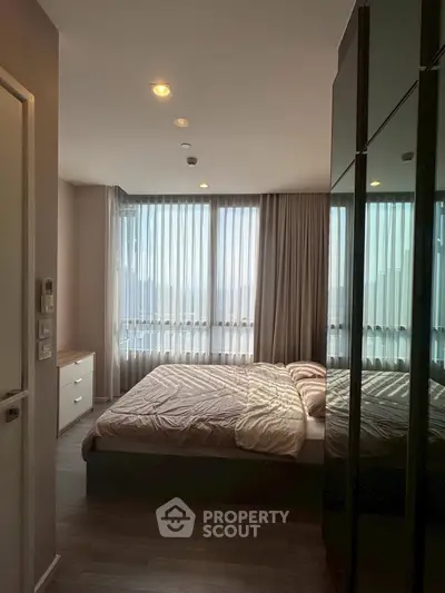 Cozy bedroom with large windows and modern decor in a stylish apartment.