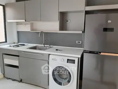 Modern kitchen with sleek cabinets, washing machine, and stainless steel fridge.