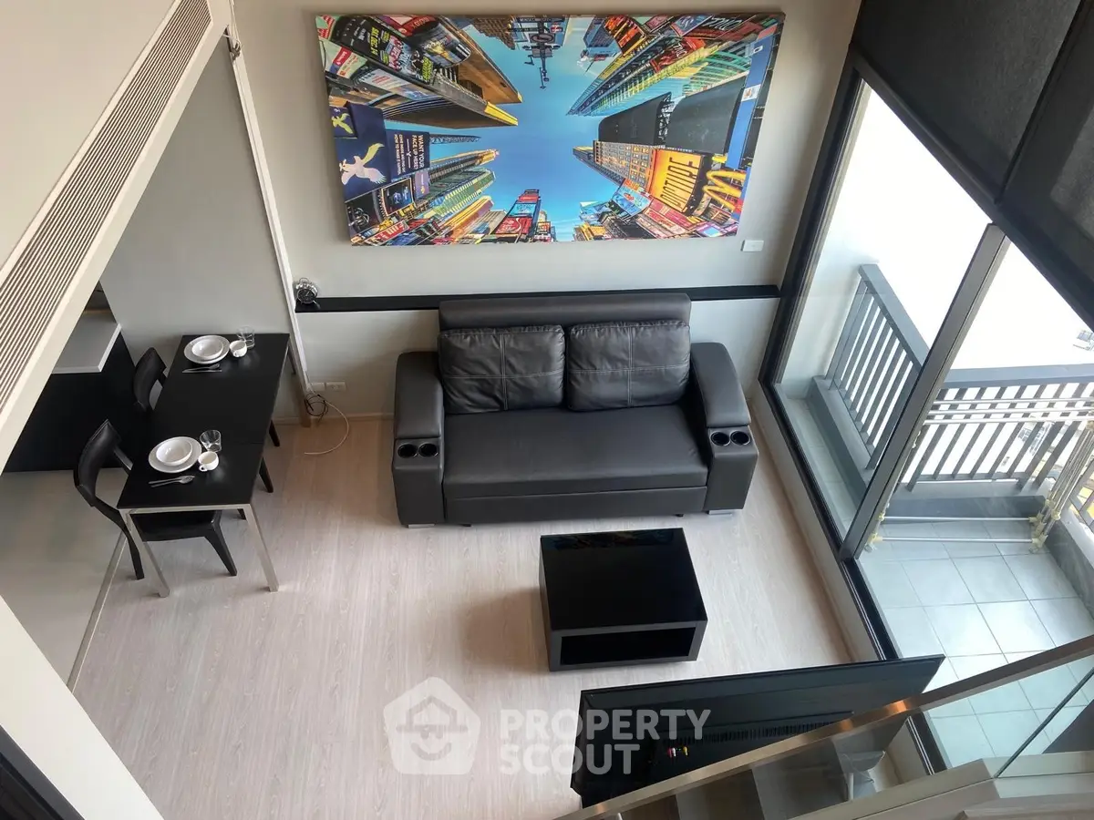 Modern loft-style living room with balcony and cityscape artwork, featuring sleek furniture and open layout.