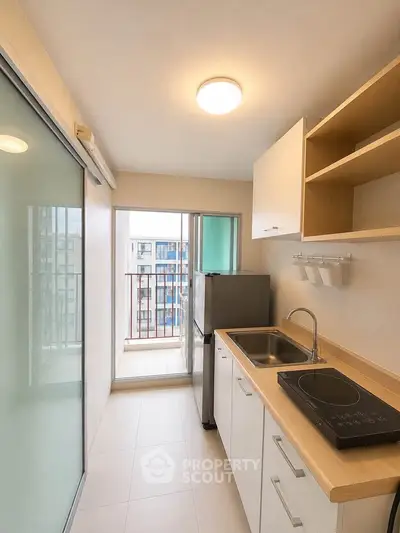 Modern kitchen with sleek design and balcony access in urban apartment