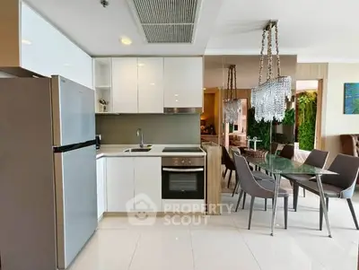 Modern kitchen with sleek white cabinets and dining area with elegant chandelier.
