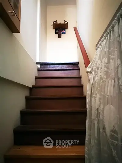 Charming staircase with wooden steps and decorative curtain in cozy home