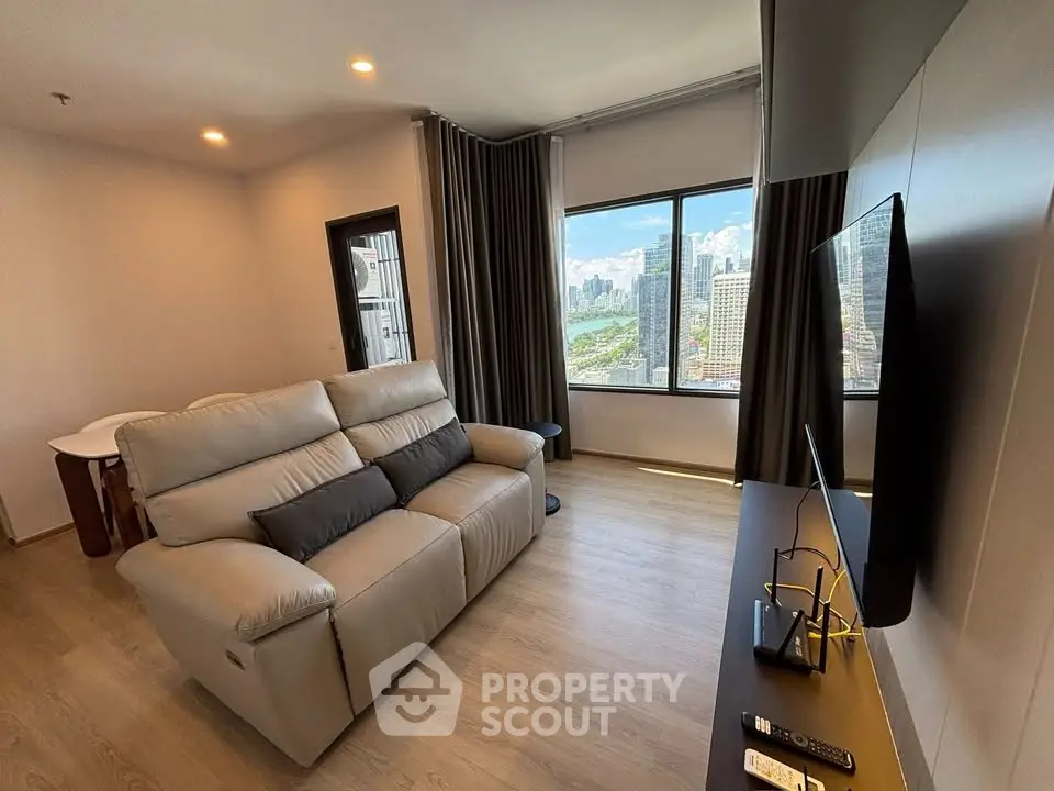 Modern living room with city view, featuring a comfortable sofa and wall-mounted TV.