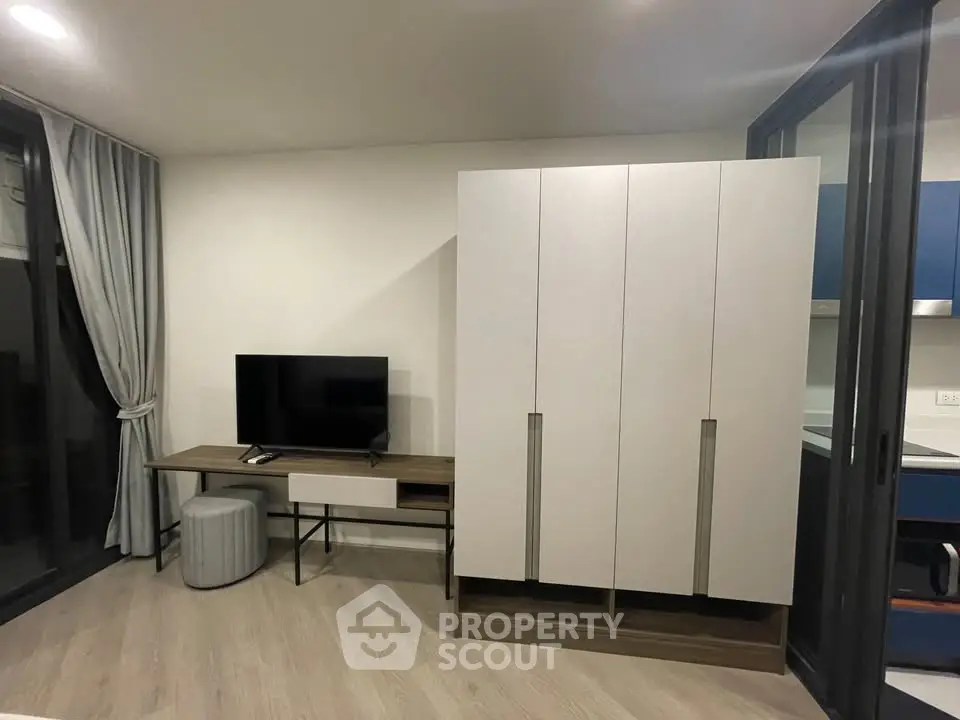 Modern living room with sleek TV stand and wardrobe, featuring floor-to-ceiling windows and elegant curtains.