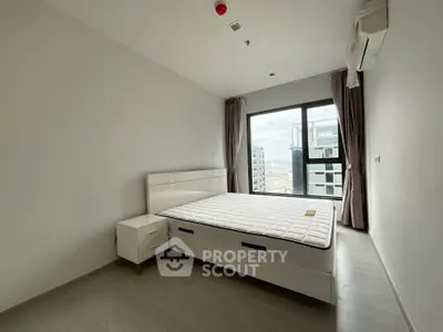 Modern bedroom with large window and city view, featuring a sleek bed and minimalist decor.