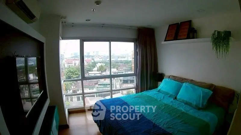Spacious bedroom with large windows offering a stunning city view, modern decor, and cozy ambiance.