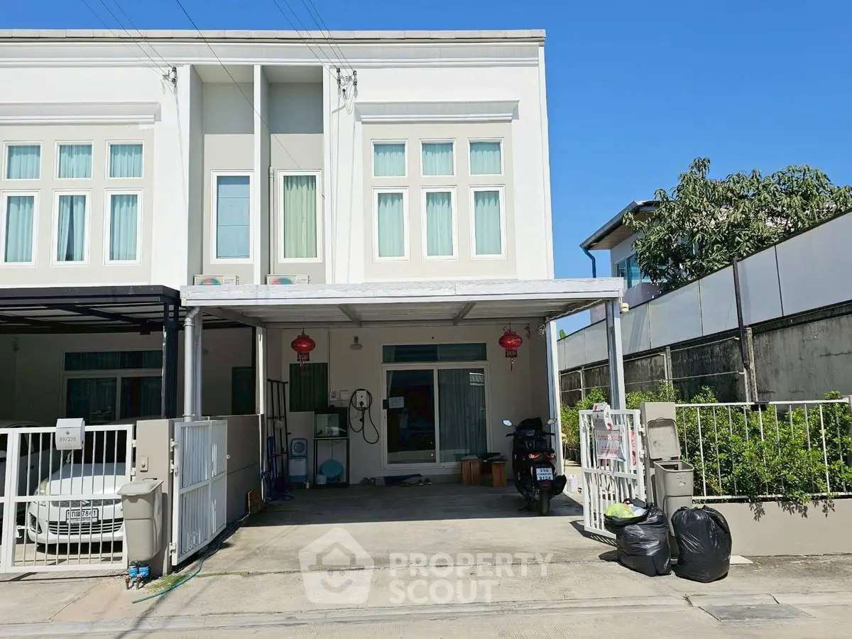 Modern townhouse with carport and gated entrance in a suburban neighborhood.