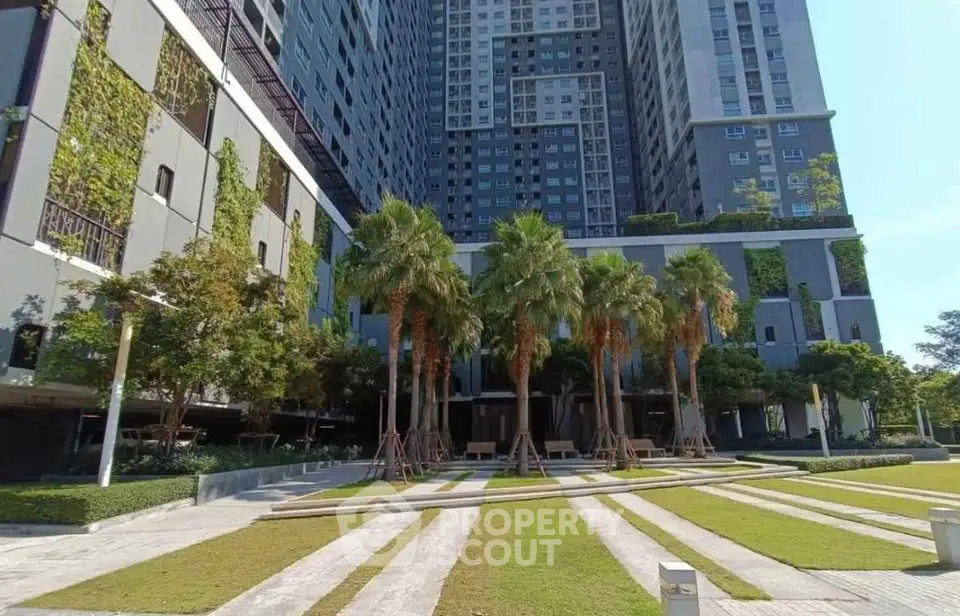 Modern high-rise building with lush greenery and palm trees in a landscaped courtyard.