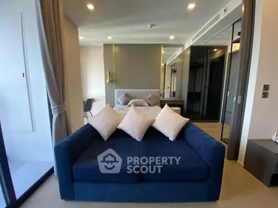 Modern studio apartment with stylish blue sofa and elegant decor, perfect for urban living.