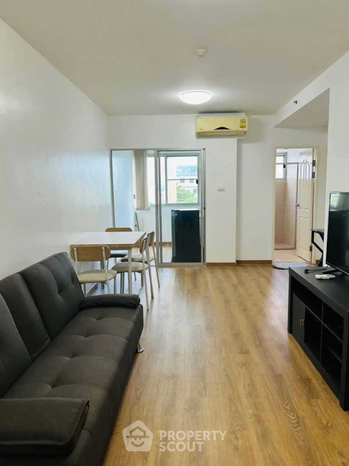 Modern living room with wooden flooring, cozy sofa, and dining area in open layout apartment.