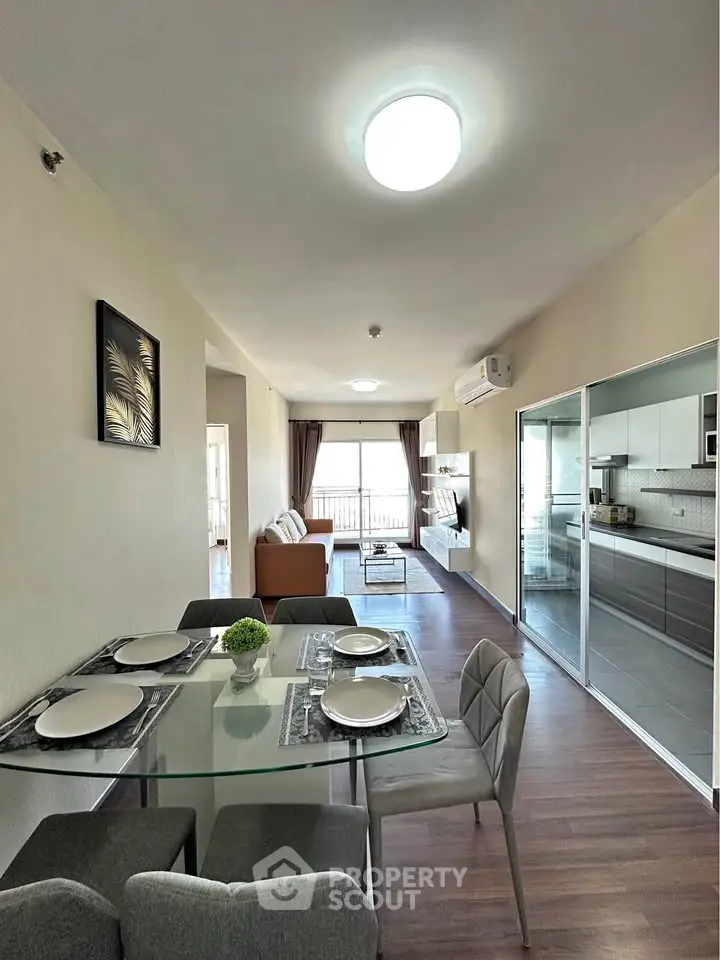 Modern open-plan living room with dining area and kitchen, featuring sleek furniture and natural light.