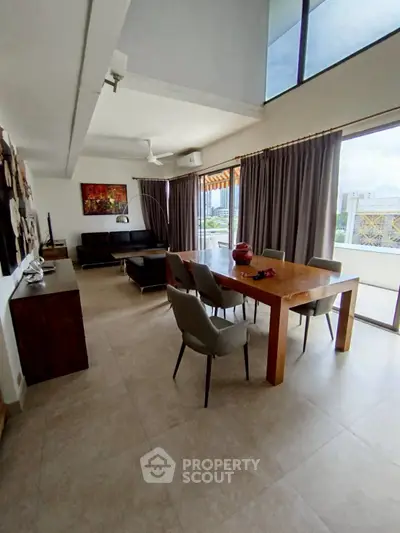 Spacious living room with modern dining area and large windows offering city views.