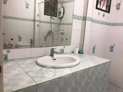 Spacious bathroom with tiled countertop and large mirror in modern home.