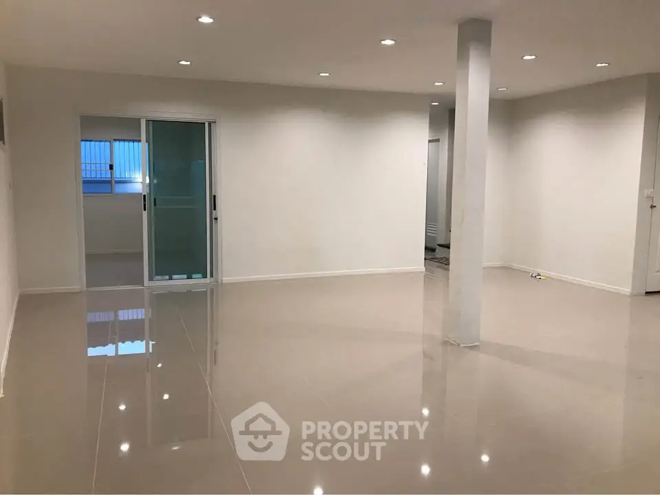 Spacious modern living room with glossy tiled floors and sliding glass doors.