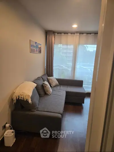 Cozy living room with modern gray sectional sofa and large window view.