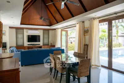 Luxurious open-plan living room with pool view, elegant furniture, and abundant natural light.