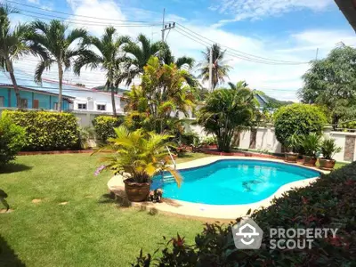 Beautiful backyard with a lush garden and inviting swimming pool under a clear blue sky.