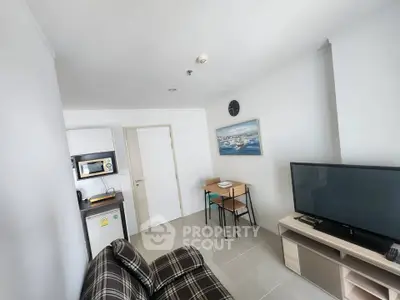 Modern living room with sleek furniture and wall art, featuring a flat-screen TV and compact dining area.