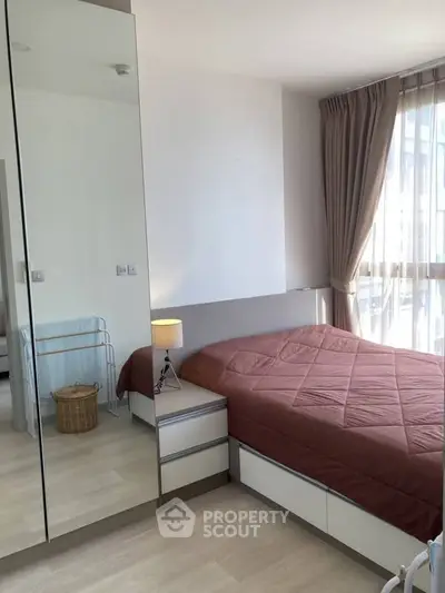 Cozy bedroom with mirrored wardrobe and natural light, perfect for relaxation.